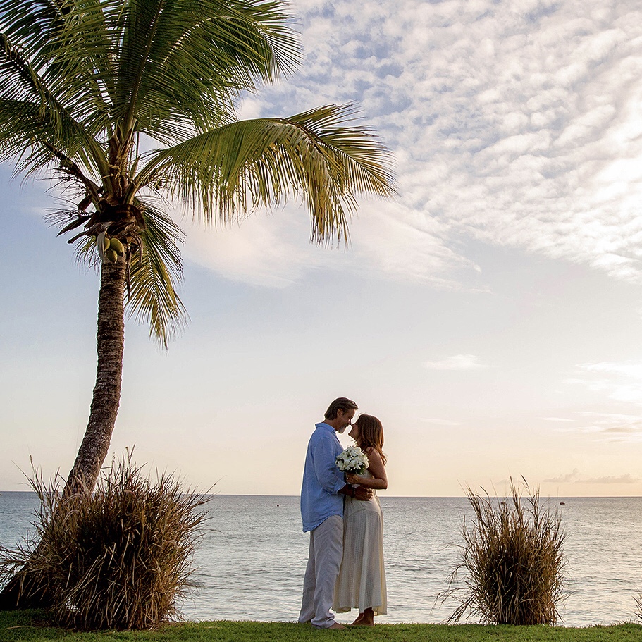 A recently married couple embracing on Enterprise Beach in Barbados during their honeymoon.